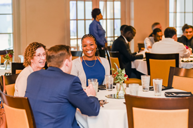 Smiling graduation attendees sitting at dinner tables