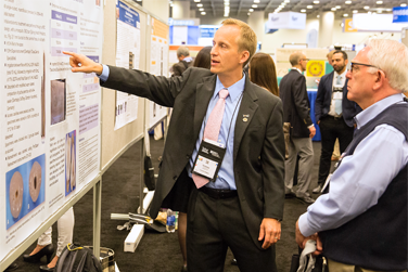 People at a gathering talking about Endodontic information on a bulletin board.