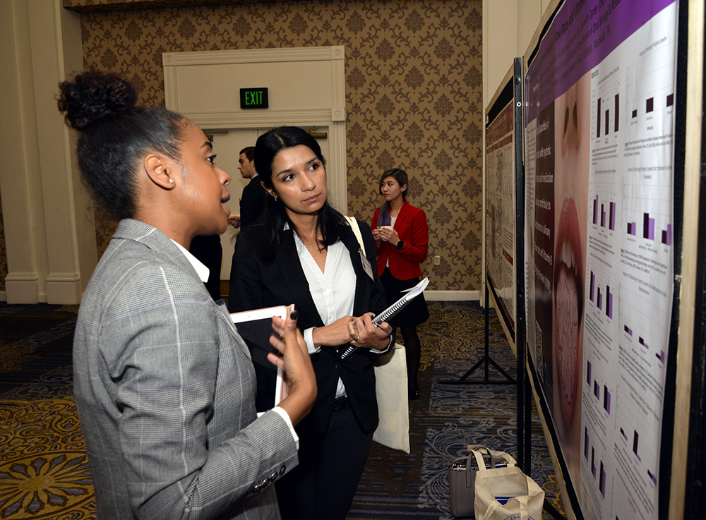 students talk in front of posterboard