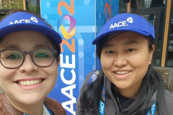 Two female fellows in front of a conference sign