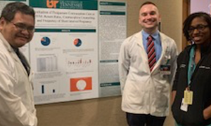 Students and faculty standing before a research poster