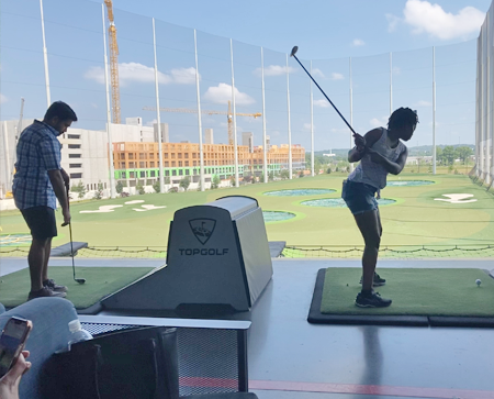 Two residents swinging golf clubs on the range