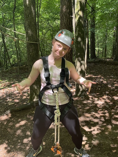 Resident outdoors wearing ziplining equipment