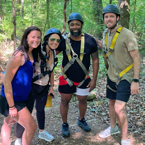 Residents in a woodsy outdoor setting with ziplining gear