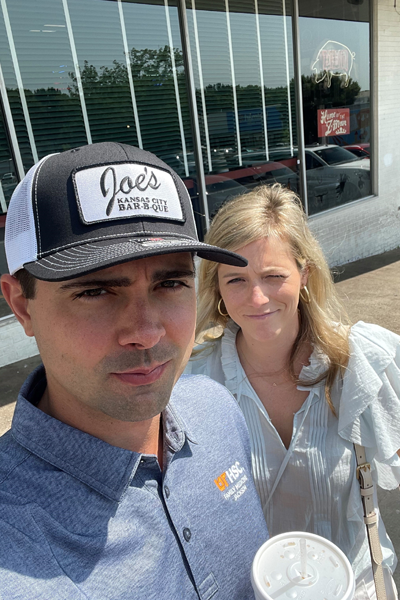 Faculty member and wife in front of a glass building