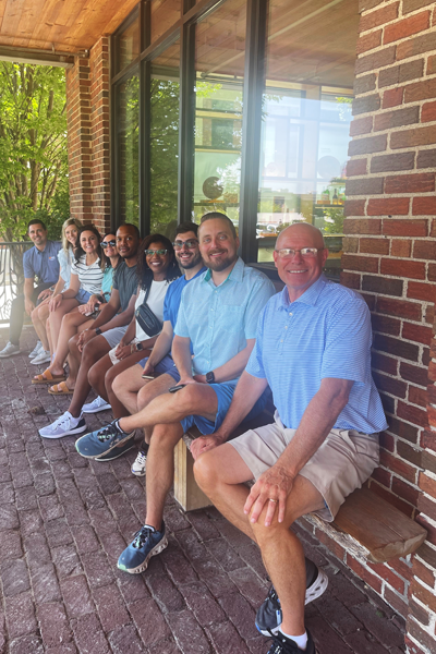 Faculty and residents sitting on a bench outside of a brick building