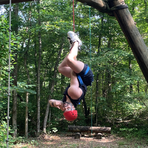 Resident hanging upside down on a ropes course