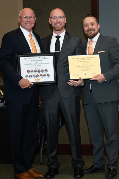 Faculty standing with a resident holding a certificate