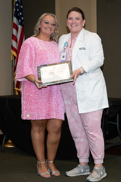 Faculty standing with a resident holding an award