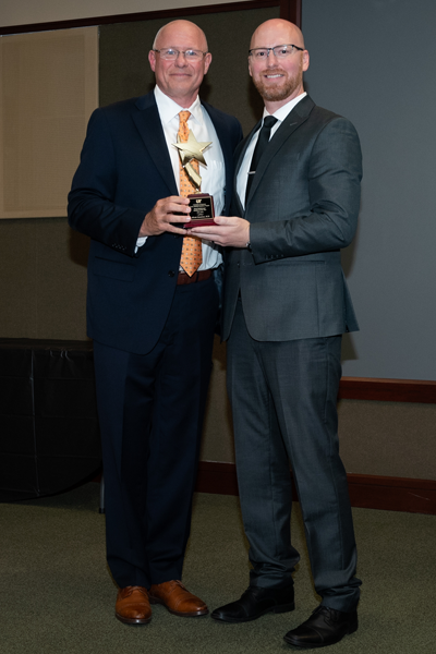 Faculty standing with a resident holding an award