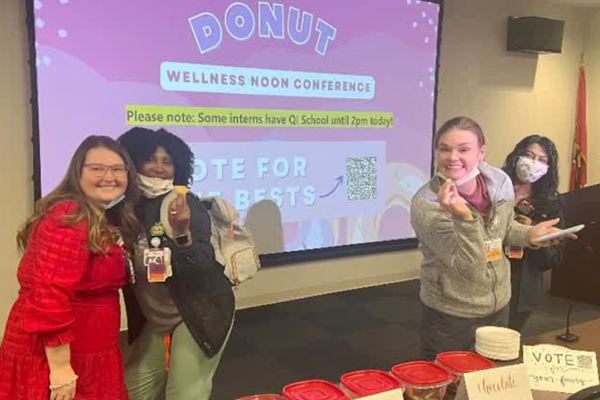 Four female residents serving donuts at a wellness noon conference