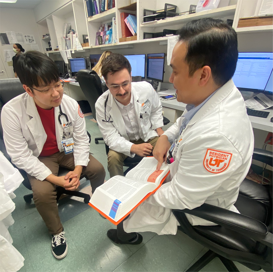 Faculty showing med students info in a book in an office setting