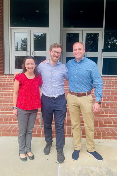 Three fellows standing outside a UTHSC building