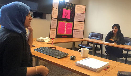 Two fellows at a table with presentation poster in the background