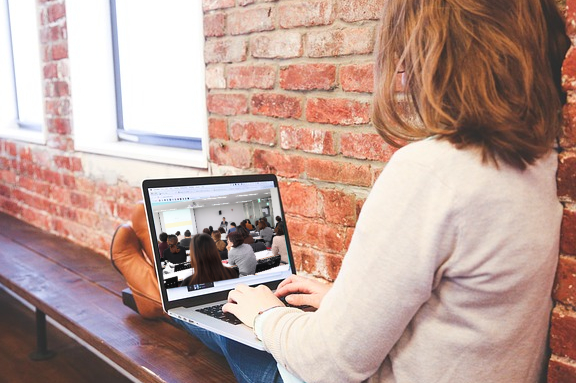 woman on computer red brick wall